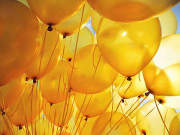 bunch of yellow balloons lit by the sun