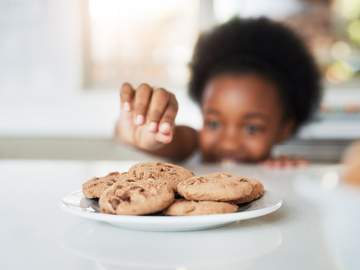 child reaching for a plate of cookies