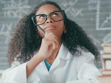 girl in lab coat in front of blackboard