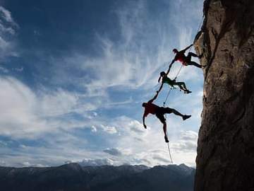 mountain climbers rappelling in a row