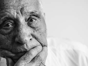 old man with sad eyes looks at the camera