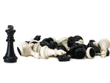 one chess piece standing next to a pile of overturned pieces