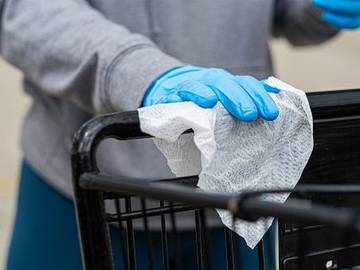 person-wiping-down-shopping-cart