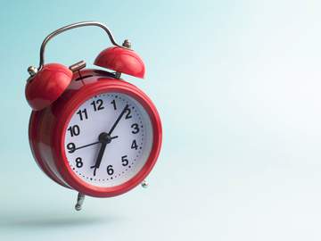 red alarm clock jumping in the air