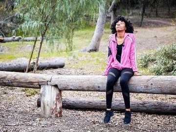 woman sitting on log in woods