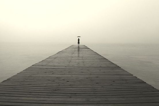 a woman waits at the end of a gloomy pier does she wait for charon the ferryman to the underworld it is dark but she carries a parasol