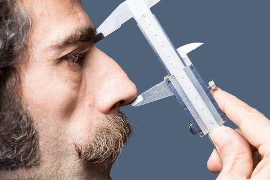close up photo of adult man nose measured with a vernier caliper 