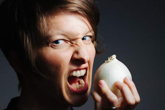 close up picture of short haired white woman biting into onion