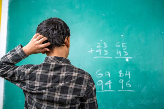 confused young man staring at blackboard