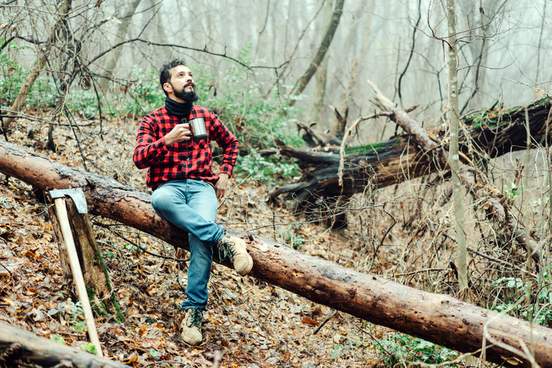contented lumberjack sits on a log
