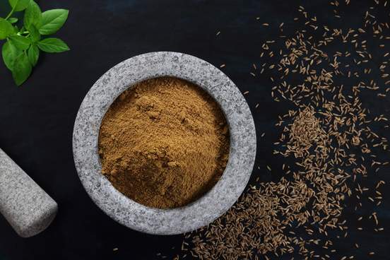 cumin seeds ground in a mortar and pestle