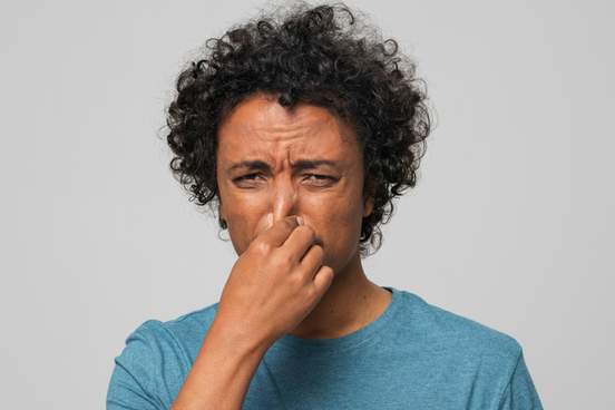distressed looking man holding his nose