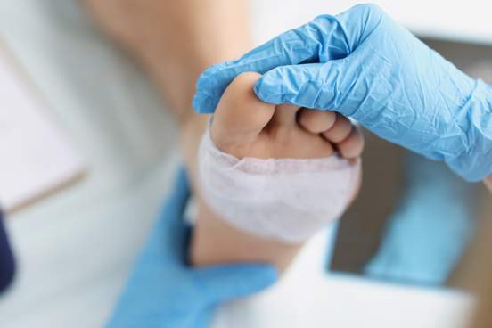 doctor inspects a foot with a bandage around it