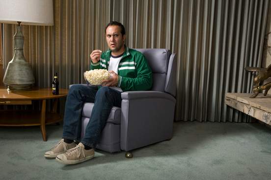 doubtful looking man sitting in chair eating popcorn