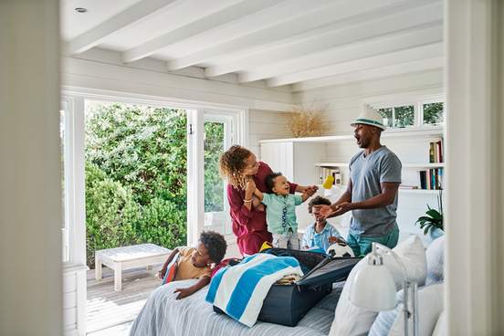 family getting ready to travel for a trip packing beach holiday toys in a suitcase in a home bedroom 