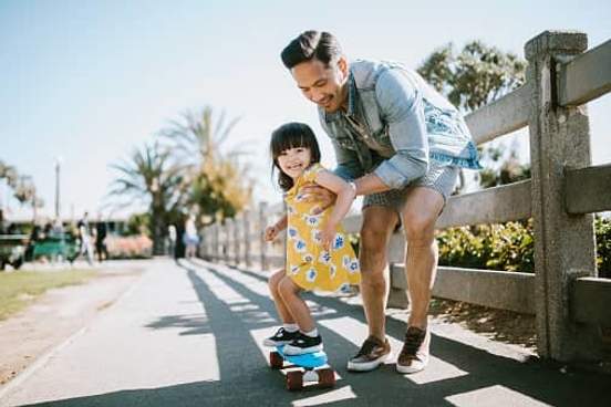 father helping daughter skateboard