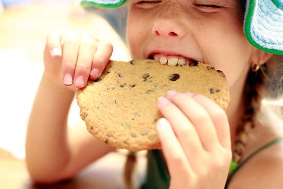 girl eating a large cookie