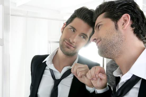 handsome narcissistic proud young man looking at himself in the mirror