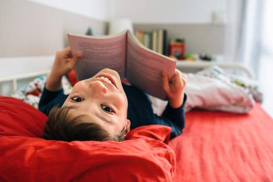 happy boy reading in bed