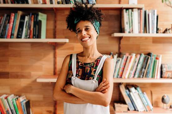 happy young woman standing in front of wall of books