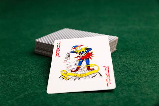 joker playing card upturned on top of a deck of other playing cards