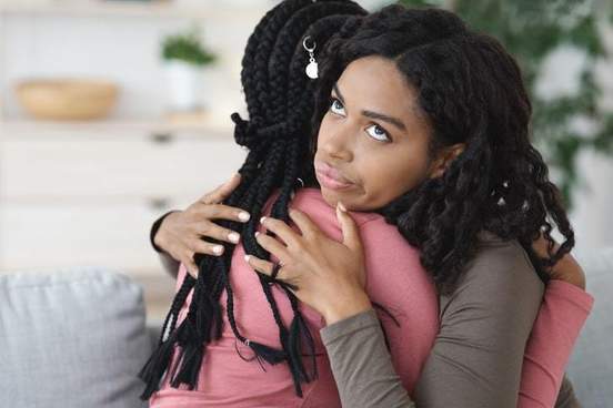 lady looking irritated while hugging her friend
