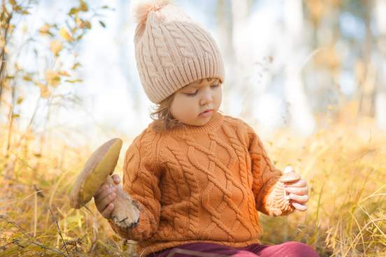 little girl in forest picking edible mushroom