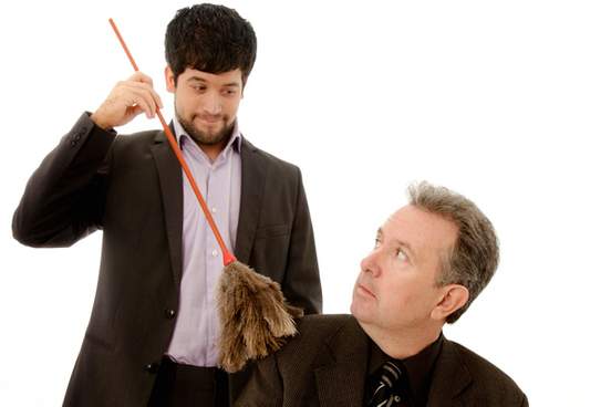 man brushing off his bosss back with feather duster