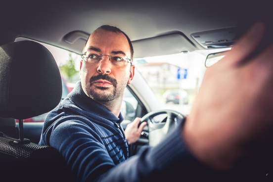 man driving car backwards