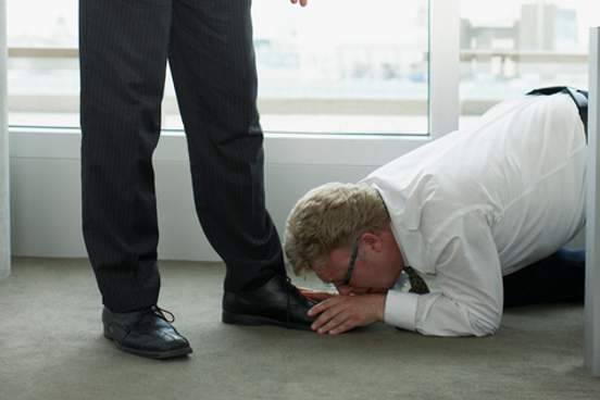 man licking his bosss shoes