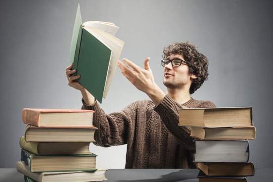 man lifting a book from the table pointing his hand on a page