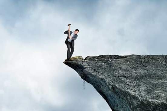 man on edge of cliff chipping away the part hes standing on