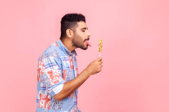 man poised to lick a garish lollipop
