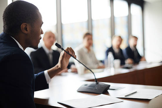 man talking into mic at business meeting