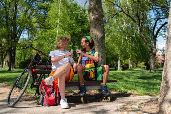 men sitting on a park bench drinking beer