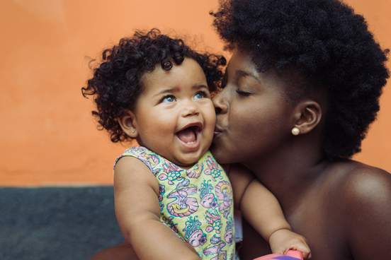 mother kissing smiling baby girl