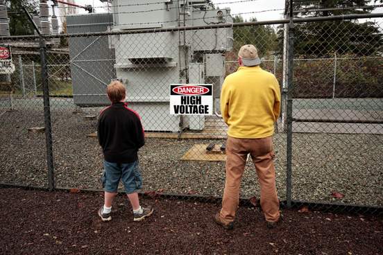 older man and younger man urinating on a high voltage fence
