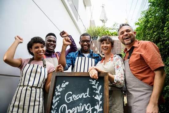 people celebrating behind grand opening sign