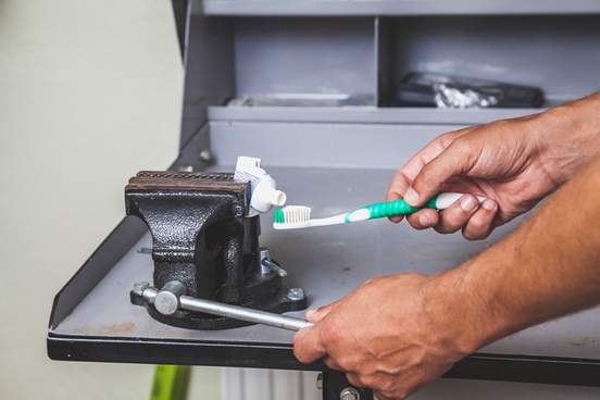 person squeezing toothpaste in a vise