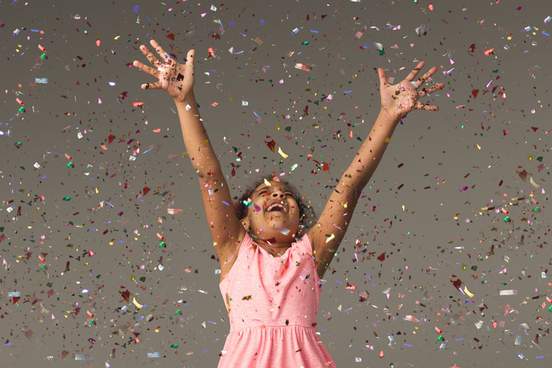portrait of beautiful child having fun with shiny confetti