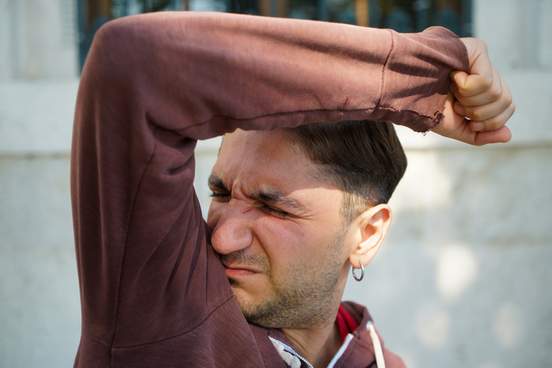 shot of a handsome young man smelling his armpits