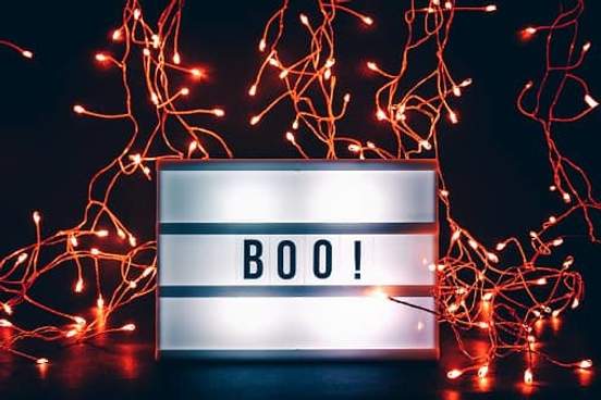 sign that says boo surrounded by orange string lights
