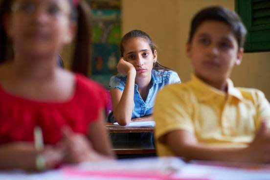 student in the back of the classroom looking bored