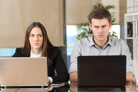 two businesspeople sit next to each other looking angry