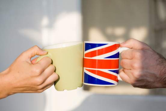 two mugs cheersing one has british flag on it