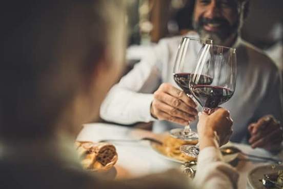 two people clinking wine glasses at dinner