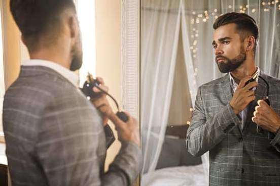 well dressed man adjusting suit in mirror