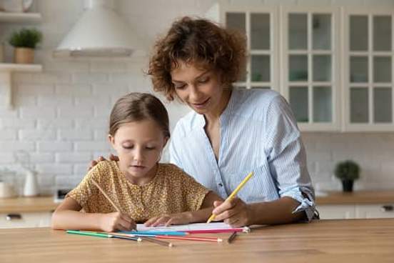 woman helping girl with schoolwork