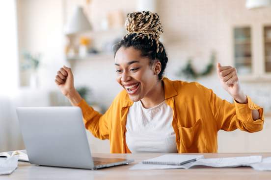 woman looking at computer and rejoicing