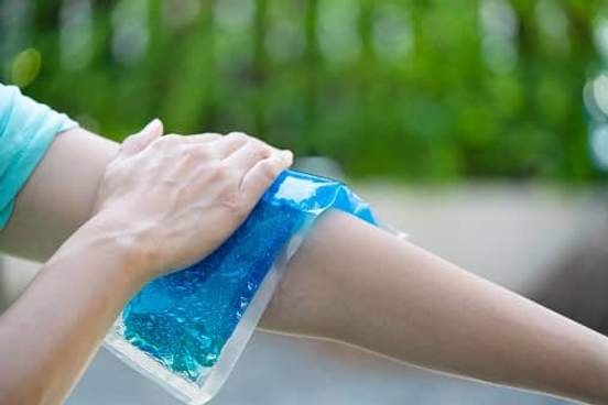 woman putting ice pack on arm
